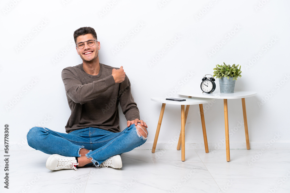 Young caucasian man sitting in his home isolated on white background pointing back Young caucasian man sitting in his home isolated on white background pointing back