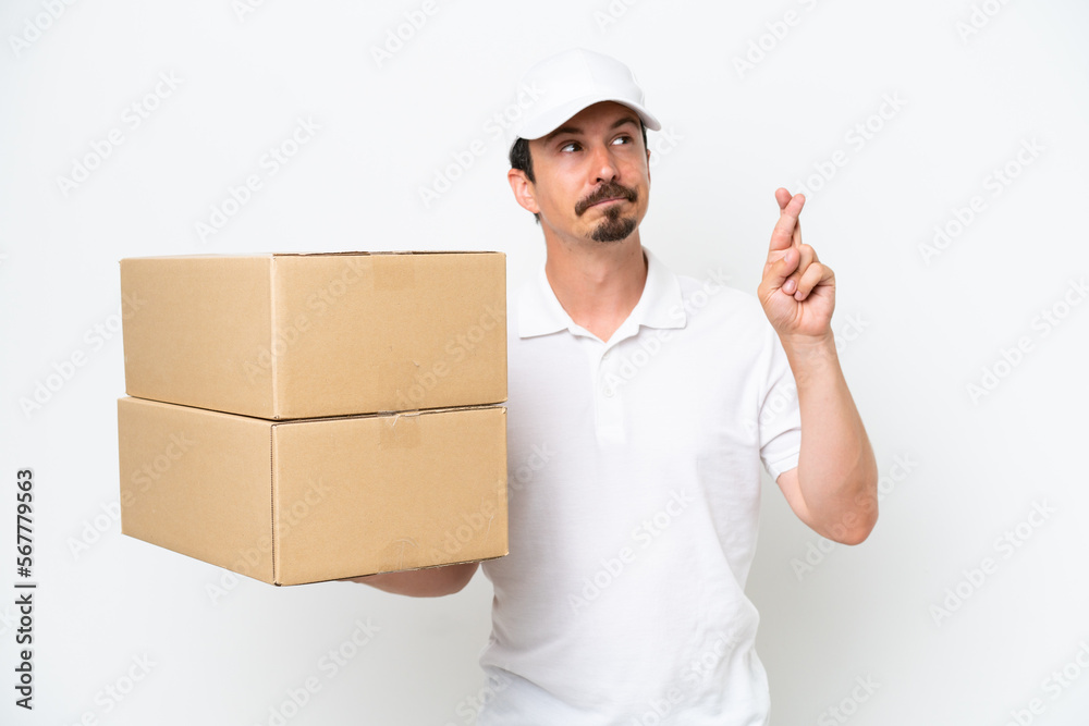 Delivery caucasian man isolated on white background with fingers crossing and wishing the best Delivery caucasian man isolated on white background with fingers crossing and wishing the best