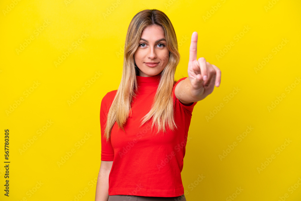 Young Uruguayan woman isolated on yellow background counting one with serious expression Young Uruguayan woman isolated on yellow background counting one with serious expression