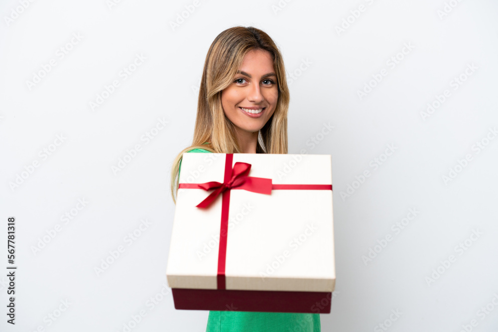 Young Uruguayan woman holding a gift isolated on white background with happy expression Young Uruguayan woman holding a gift isolated on white background with happy expression