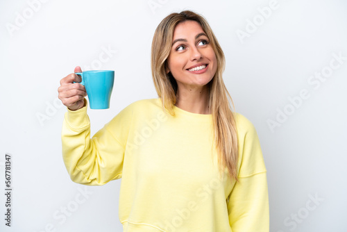 Young Uruguayan woman holding cup of coffee isolated on white background looking up while smiling