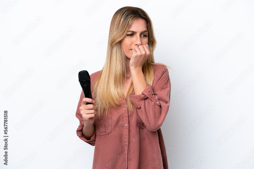 Singer Uruguayan woman picking up a microphone isolated on white background having doubts Singer Uruguayan woman picking up a microphone isolated on white background having doubts