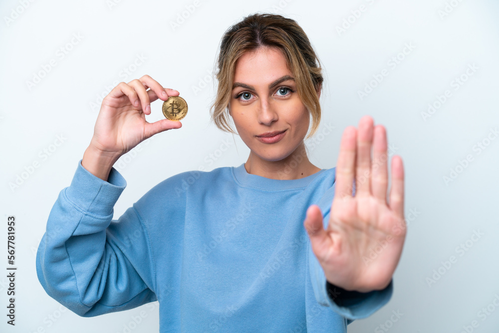 Fototapeta premium Young Uruguayan woman holding a Bitcoin isolated on white background making stop gesture