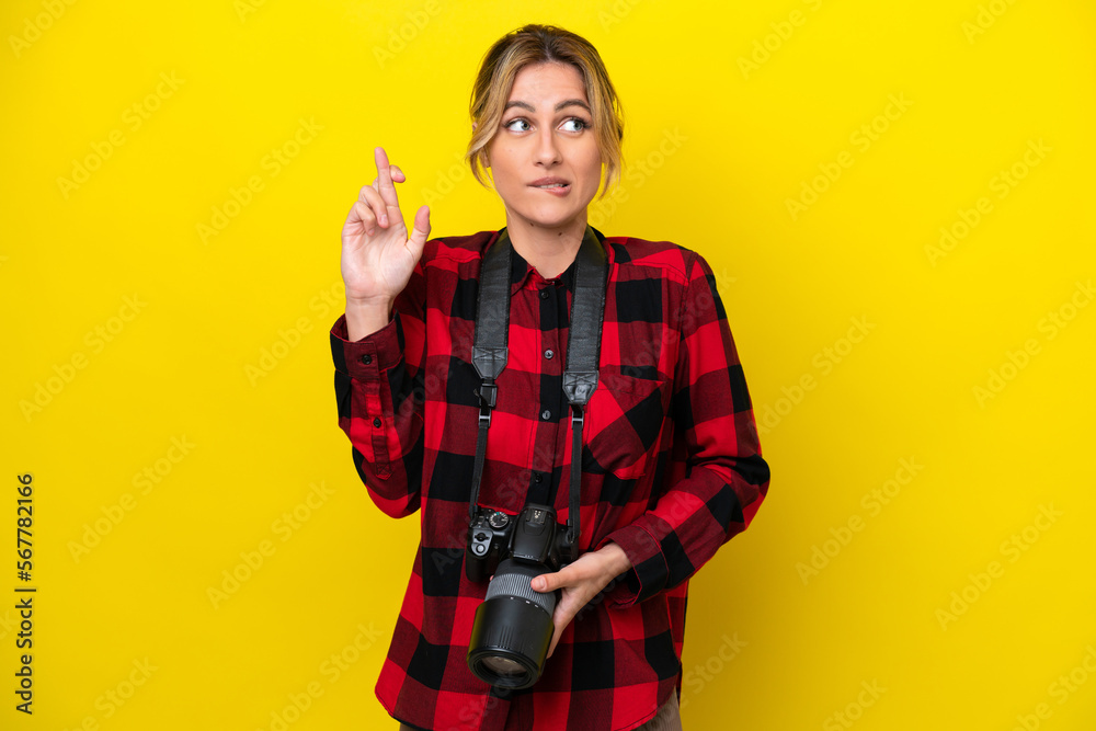 Uruguayan photographer woman isolated on yellow background with fingers crossing and wishing the best Uruguayan photographer woman isolated on yellow background with fingers crossing and wishing the best