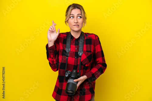 Uruguayan photographer woman isolated on yellow background with fingers crossing and wishing the best
