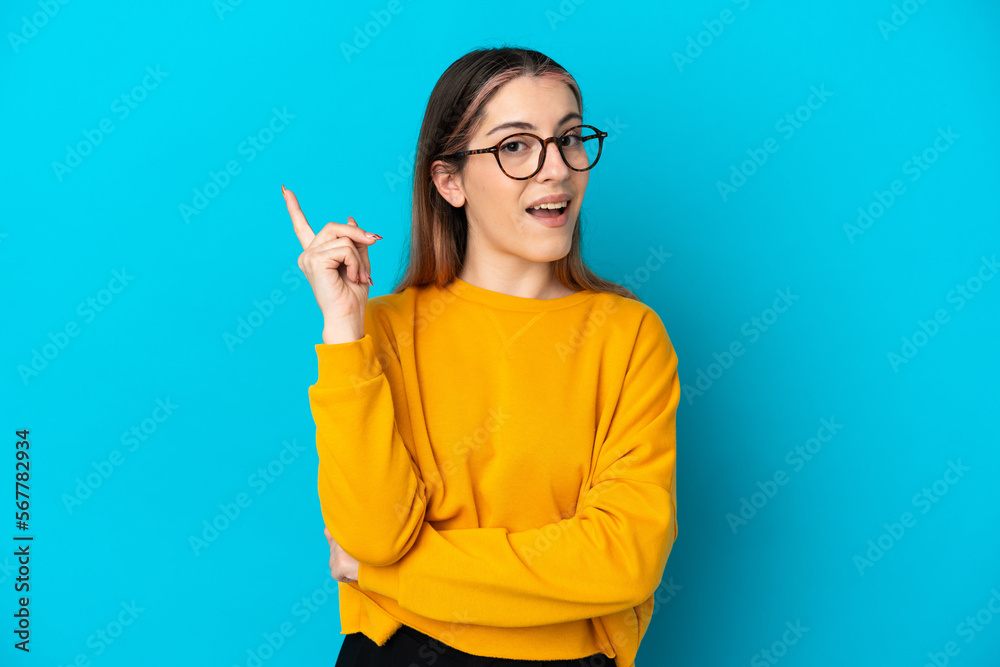 Young caucasian woman isolated on blue background intending to realizes the solution while lifting a finger up Young caucasian woman isolated on blue background intending to realizes the solution while lifting a finger up