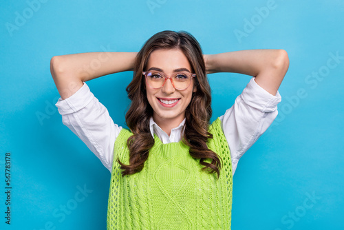 Portrait of satisfied glad young person beaming smile arms behind head accomplish work isolated on blue color background