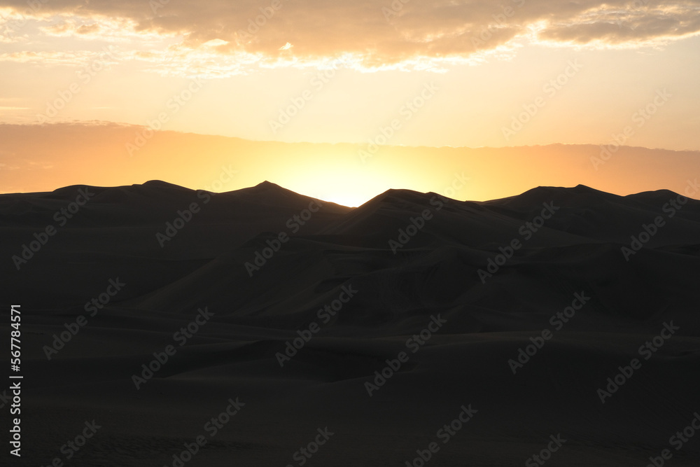 Sunset at Huacachina desert in Peru. Desert sunset landscape background silhouette photography. Golden hours at sandy mountains.