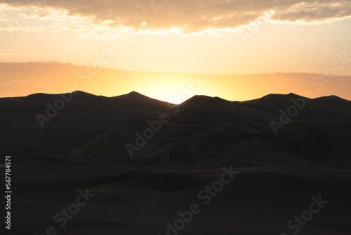 Sunset at Huacachina desert in Peru. Desert sunset landscape background silhouette photography. Golden hours at sandy mountains.