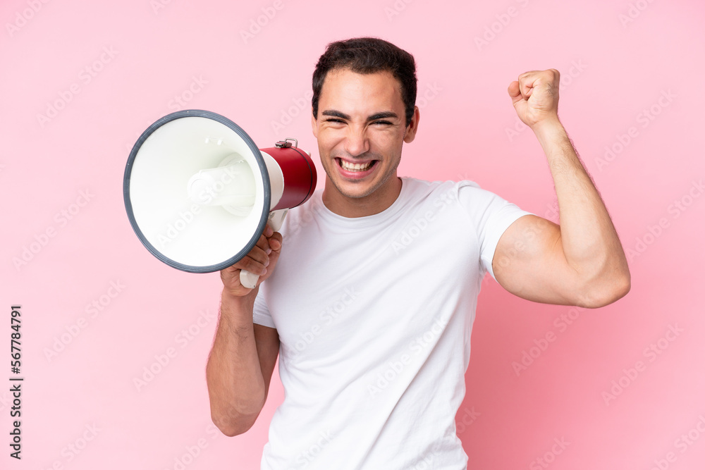 Young caucasian man isolated on pink background shouting through a megaphone to announce something Young caucasian man isolated on pink background shouting through a megaphone to announce something
