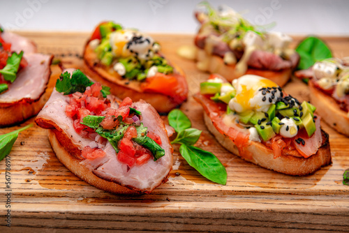 Traditional italian antipasto bruschetta appetizer with meat, fish, greens and balsamic vinegar.