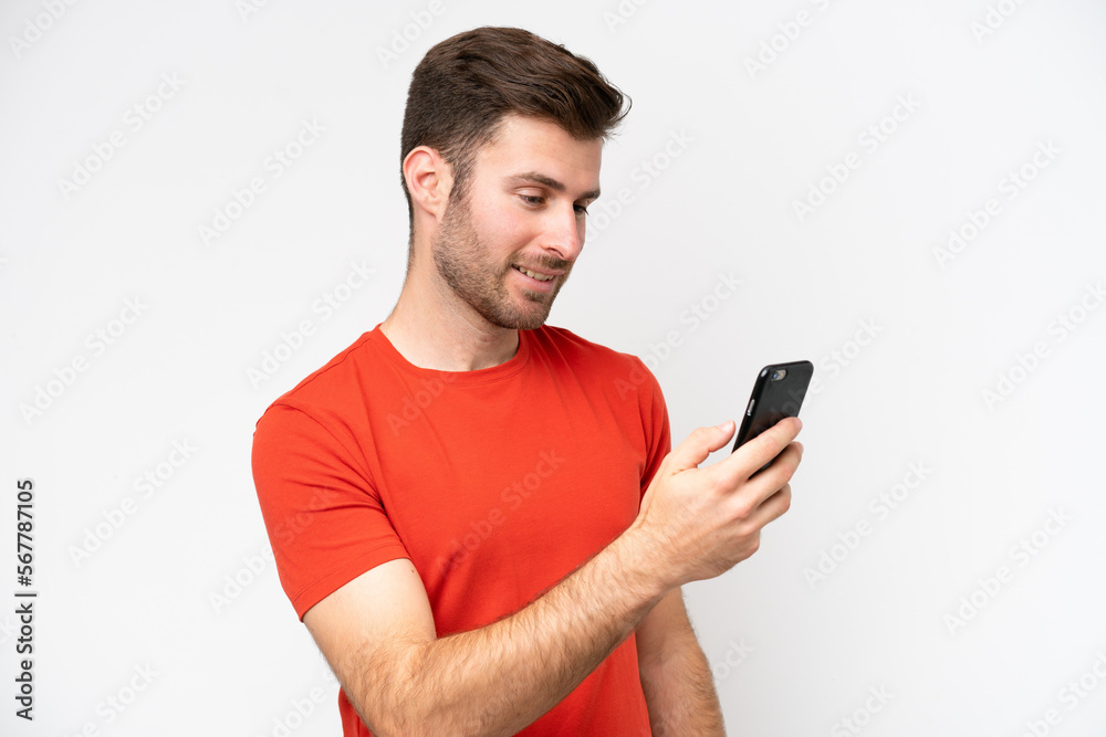 Young caucasian man isolated on white background sending a message or email with the mobile Young caucasian man isolated on white background sending a message or email with the mobile