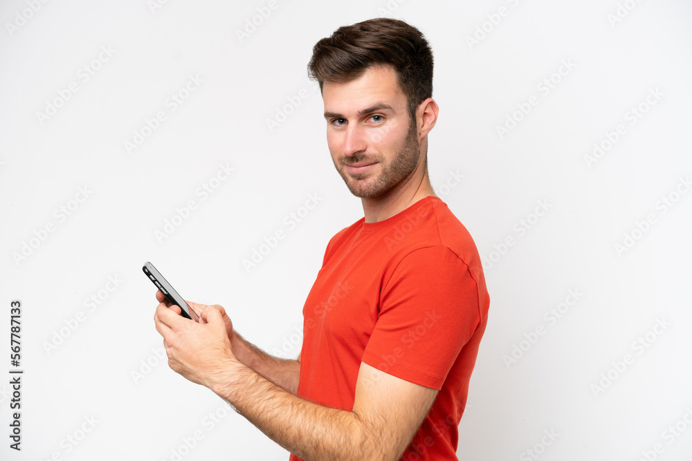 Young caucasian man isolated on white background sending a message or email with the mobile Young caucasian man isolated on white background sending a message or email with the mobile
