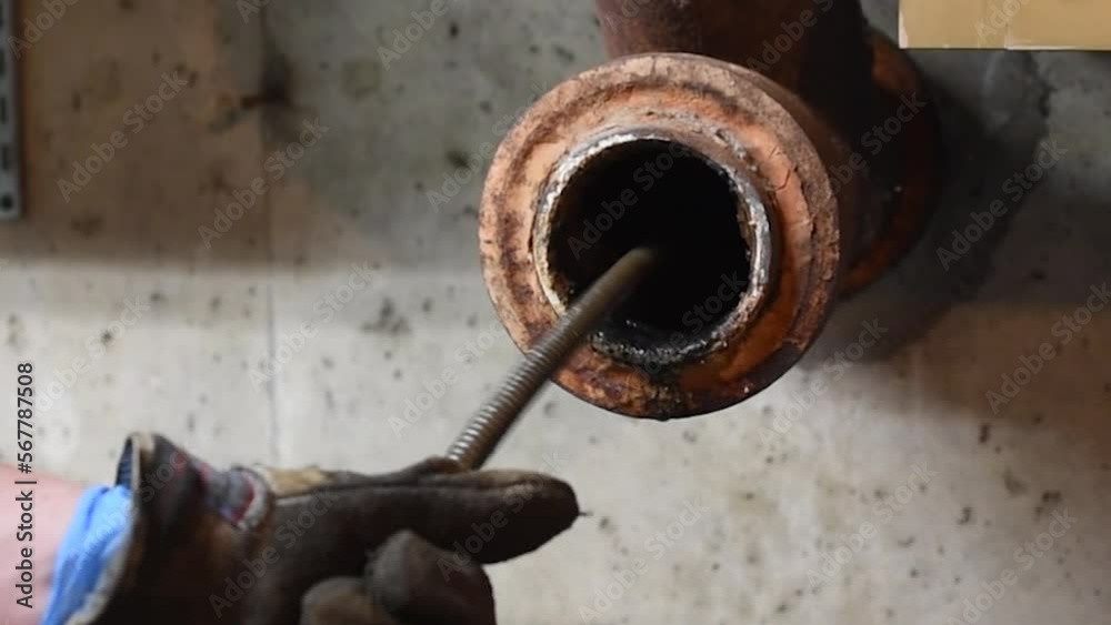 Hands of a plumber as he runs a camera scope and cleaning machine through the main pipe to unclog the drain to the Septic System. Hard-working tradesman.