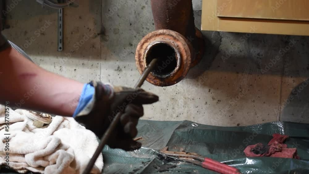 Hands of a plumber as he runs a camera scope and cleaning machine through the main pipe to unclog the drain to the Septic System. Hard-working tradesman.