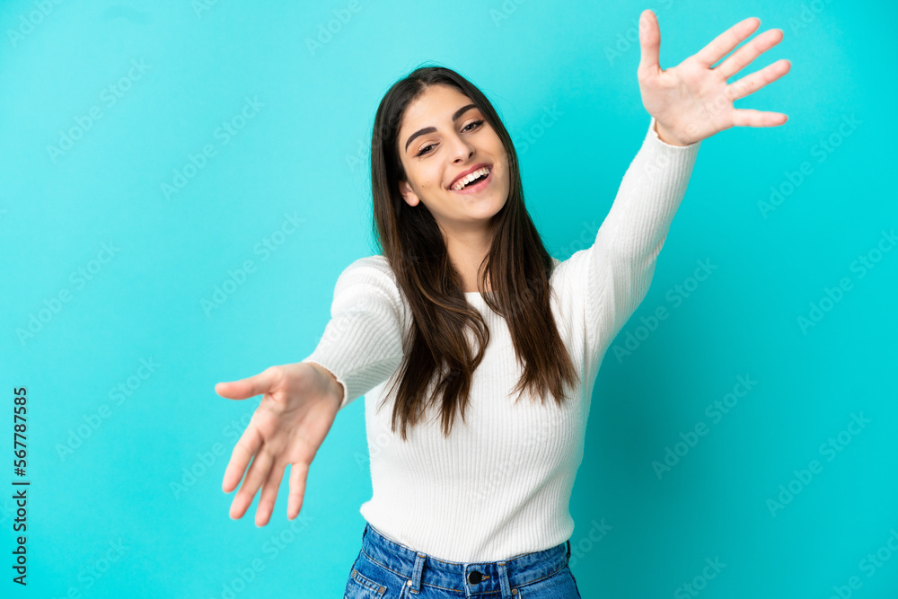 Young caucasian woman isolated on blue background presenting and inviting to come with hand