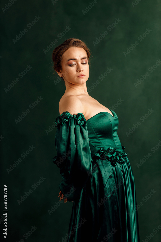 waist portrait of a girl in a green dress standing against a green wall