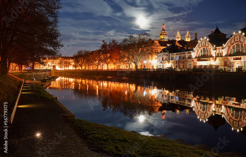 he illuminated building of the "Hucak" hydropower plant, where the museum is located today. In the background is the most famous panorama of Hradec Kralove with the White Tower. illuminated full moon