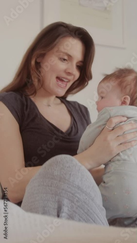 New Mum Lifting her Baby and Smiling in Bed at Home