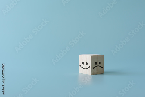 Concept of customer satisfaction review. Wooden blocks with facial expression with Happy and sad mood. To evaluate business performance you need a survey from customer experience.