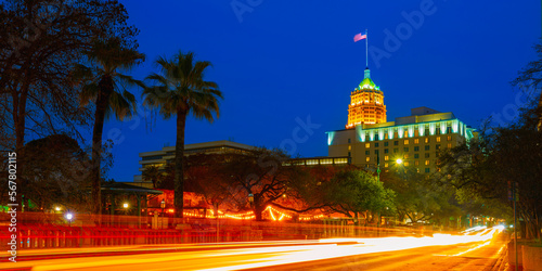 San Antonio Texas night street landscape with car light trails, skyline buildings, waving American flag, and palm trees in winter