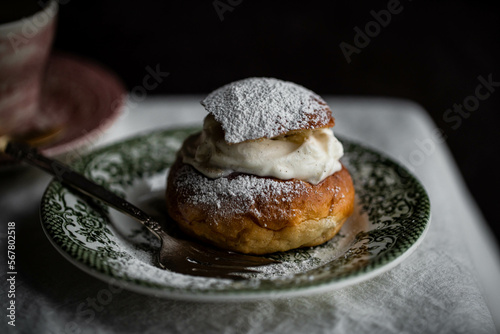 Homemade semla bun with frangipane and whipped cream on vintage plate. photo