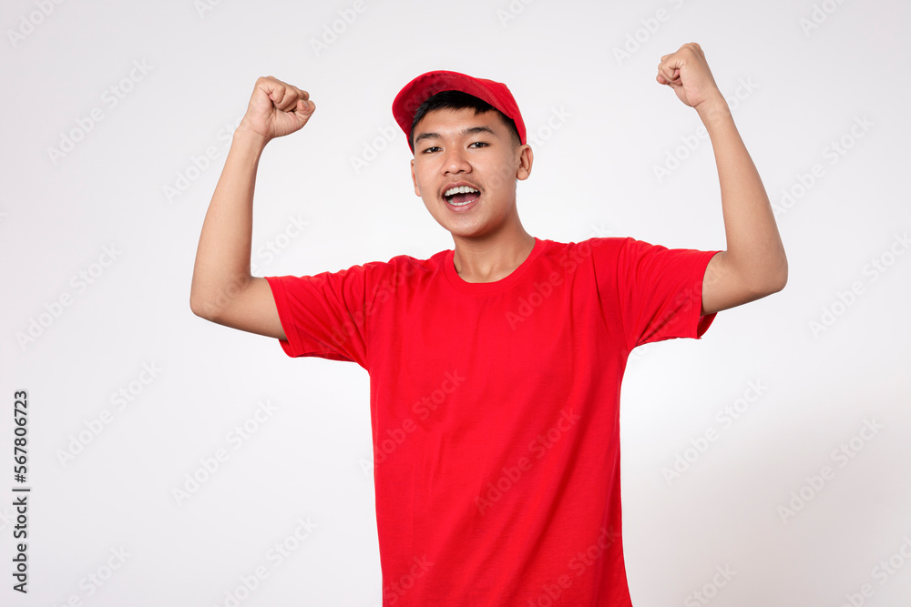 Celebration concept. Smiling young asian Delivery man in red uniform isolated on white background very happy and excited celebrating a victory with arms raised