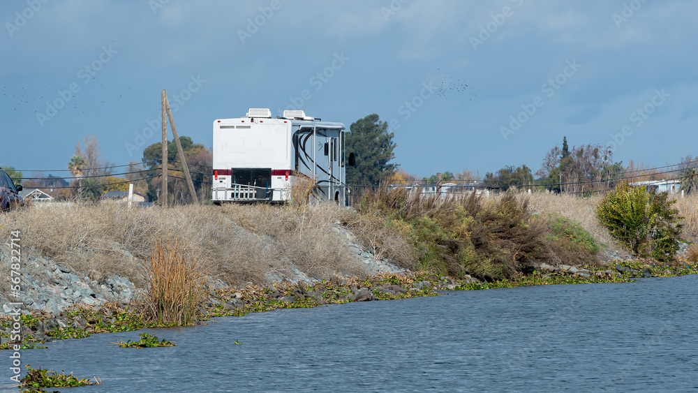 Rv traveling down levee road with water and levee wall