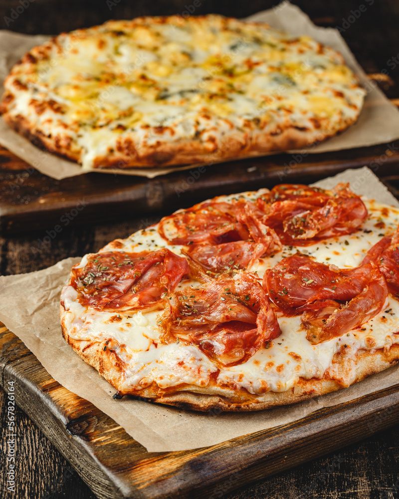 Two Roman-style pizzas with cheese and jamon serrano. Roman square pizza or Pinsa on thick dough, Italian cuisine Two Roman-style pizzas with cheese and jamon serrano. Roman square pizza or Pinsa on thick dough, Italian cuisine