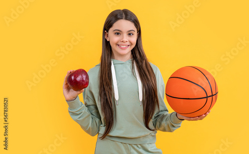 photo of happy teen basketball girl with apple. teen basketball girl isolated on yellow.