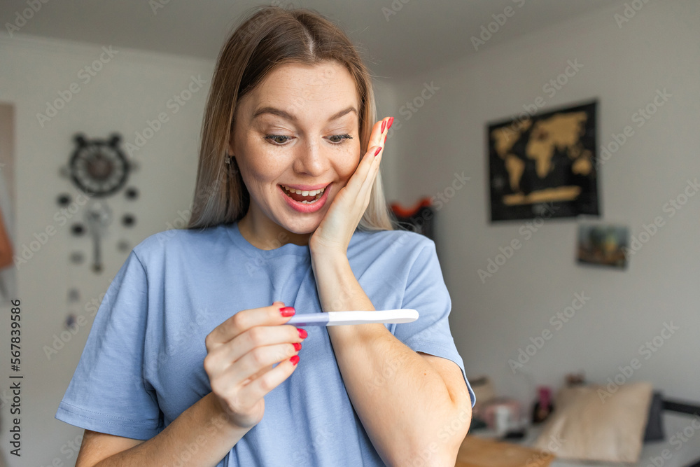 Delighted and surprised woman holding pregnancy test Delighted and surprised woman holding pregnancy test