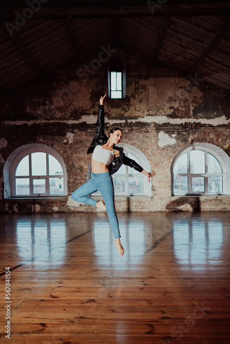 Fototapeta Naklejka Na Ścianę i Meble -  Woman jumping in casual style doing ballet in old studio. Attractive ballerina