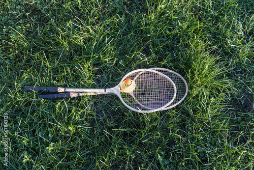 Pair of badminton rackets with white shuttlecock on the green grass children's playground in the yard in summer