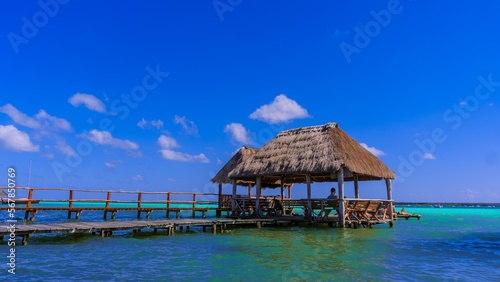 Palapa sobre la laguna azul de Bacarlar con nuves al fondo