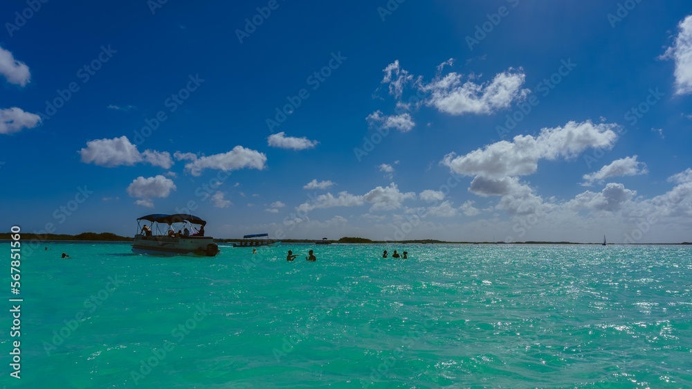 Fotografia de paisaje en la laguna de Bacalar con gente nadando y un pequeño bote al fondo