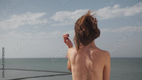 Young attractive girl without shirt contemplates the sea from a balcony at the beach in Cadiz, Andalucia, Spain.She enjoys the sun on holidays.