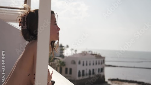 Young attractive girl without shirt contemplates the sea from a balcony at the beach in Cadiz, Andalucia, Spain.She enjoys the sun on holidays.