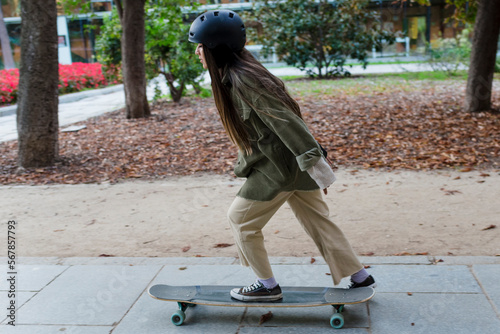 Young skateboarder woman practicing tricks with a longboard outdoors in a park. © Viviland