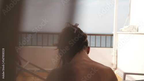 Young attractive girl without shirt contemplates the sea from a balcony at the beach in Cadiz, Andalucia, Spain. She enjoys the sun on holidays.