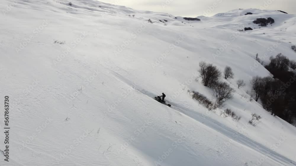 A man on a snowmobile roams the mountains 2023 filming from a drone A man on a snowmobile roams the mountains 2023 filming from a drone