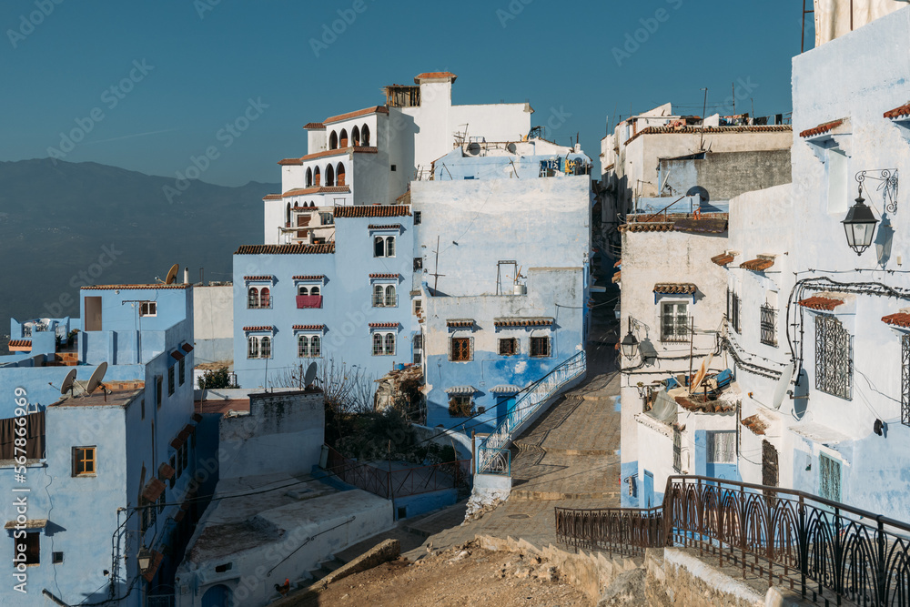 Outskirts of the old city are multi-storey buildings with white and blue walls of various shades. Broken road in potholes. Empty ancient city in the morning is flooded with sunlight.