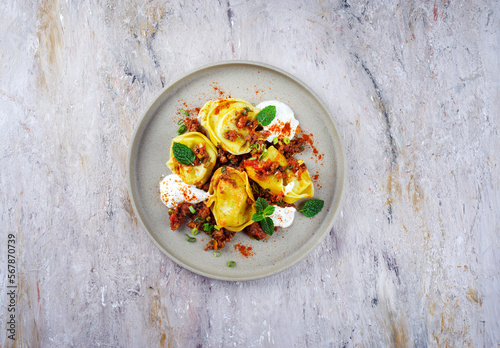 Traditional oriental manti dumplings with spicy minced meat and yogurt served as top view in a Nordic design plate with text free space photo