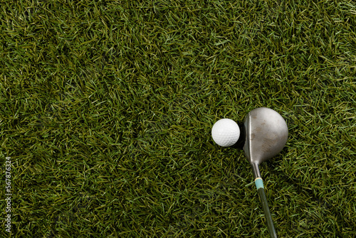 White golf ball and golf club on grass with copy space