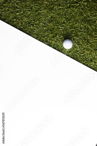 High angle view of white golf ball on grass with copy space on white background