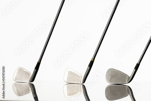 Close up of three golf clubs with copy space and reflection on white background