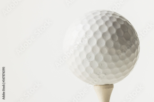 Close up of white golf ball on golf tee with copy space on white background