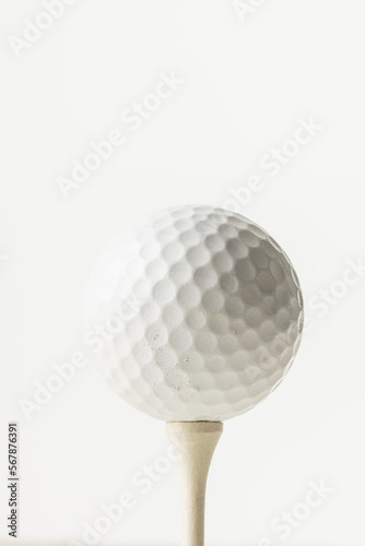Close up of white golf ball on golf tee with copy space on white background