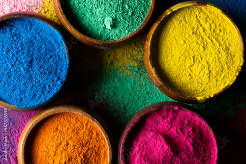Close up of multi coloured powder in bowls and copy space on black background