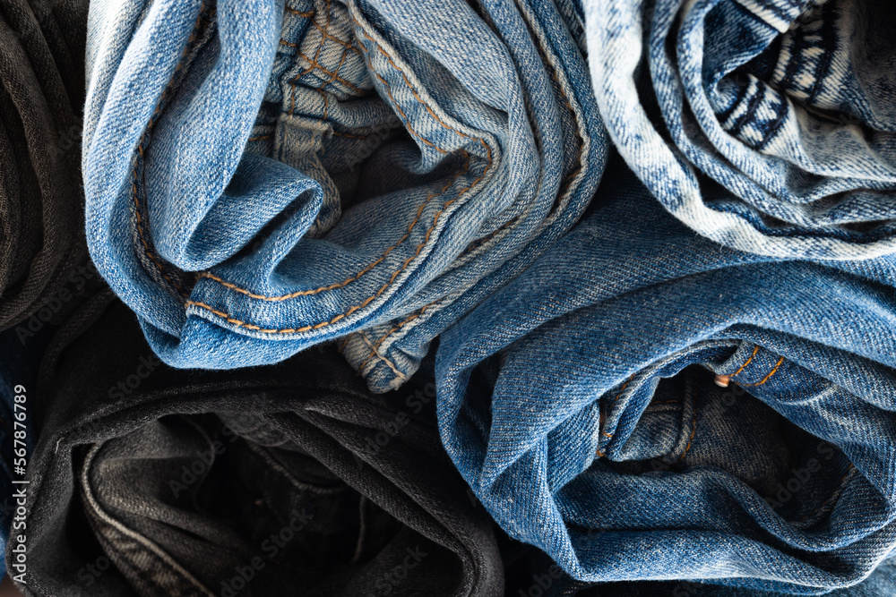 Close up of diverse folded jeans lying in stack on white background Close up of diverse folded jeans lying in stack on white background