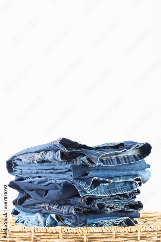 Vertical image of diverse folded jeans lying in stack on white background Vertical image of diverse folded jeans lying in stack on white background